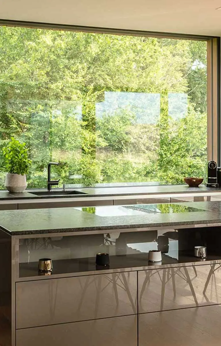 Moderne Küche mit rahmenloser Ganzglas-Fixverglasung und Blick ins Grüne