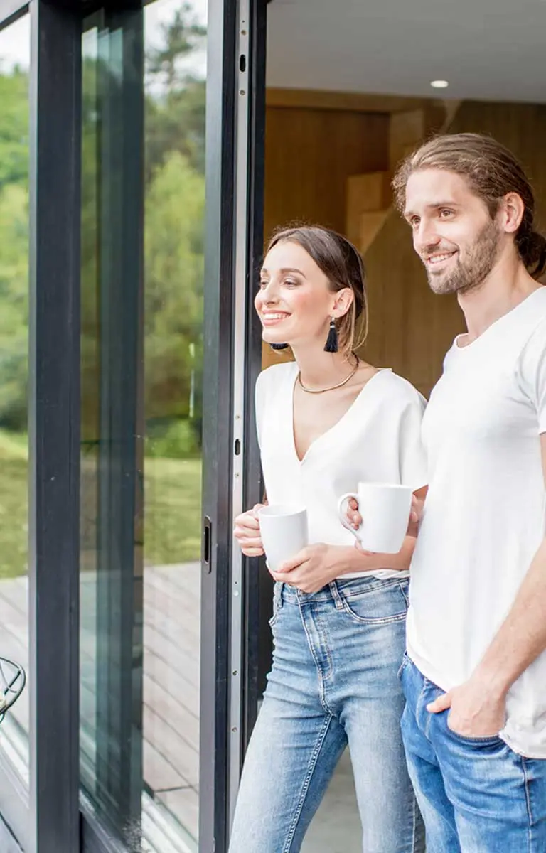 Paar steht vor großen Schiebetüren mit Blick ins Grüne