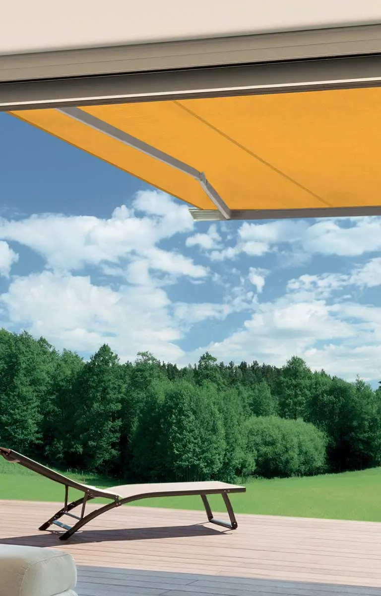 Gelbe Markise spendet Schatten auf moderner Terrasse mit Blick ins Grüne