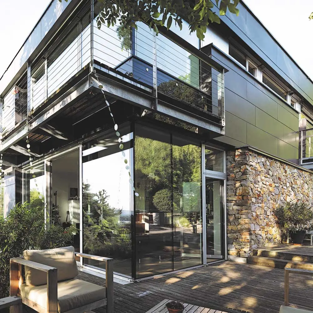 Modernes Haus mit rahmenlosen Ganzglas-Fenstern und Terrasse aus Holz.