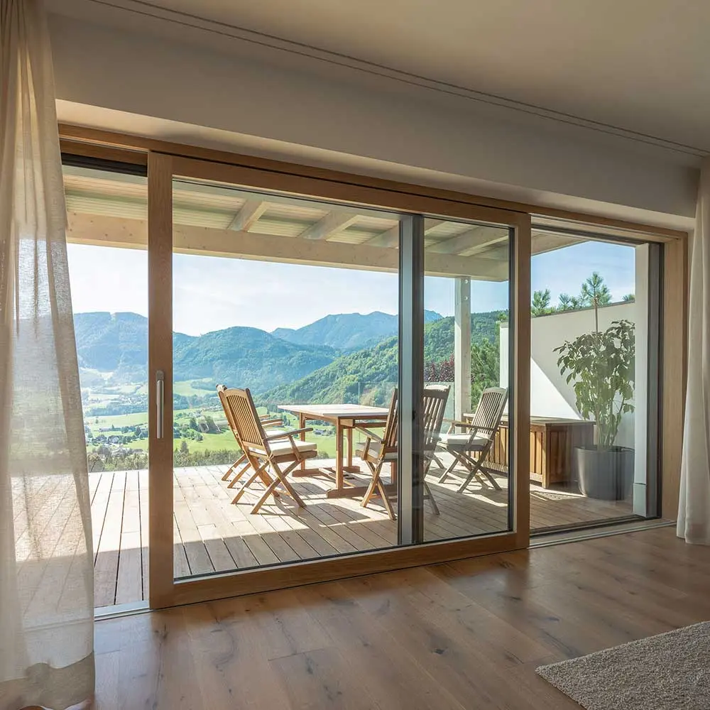 Große Holz-Alu Hebeschiebetür mit Bergblick und Terrasse, innen mit Holzrahmen.