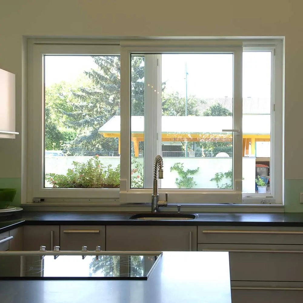 Kunststoff-Schiebefenster über Küchenarbeitsfläche mit Blick in den Garten – actual-berger.